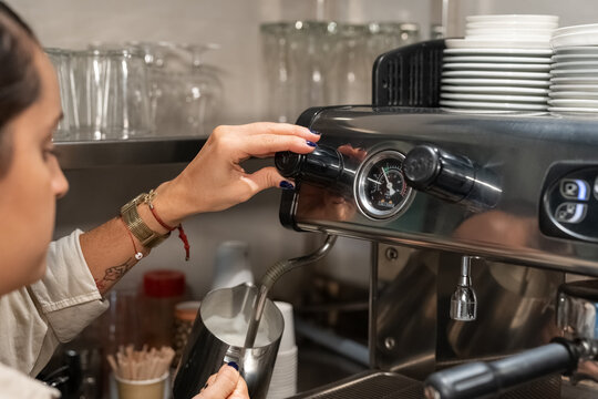 Female barista operating coffee machine control knob