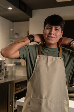 Candid barista putting on apron at cafe