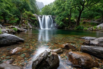 Fototapeta premium Serene Waterfall Cascading into Crystal Clear Pool Rocks and Lush Greenery