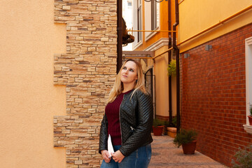 Photo shoot of a blonde woman in a black leather jacket and a burgundy sweater in the center of the...