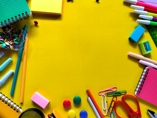 Assorted school supplies arranged on a yellow background. Back to school concept.