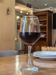 Elegant Glass of Red Wine on Table in Cozy Cafe Setting