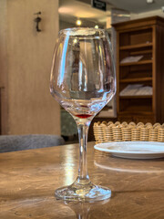 A glass with the remains of red wine on a wooden table in a cozy restaurant
