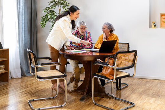 Senior couple meeting with financial advisor at home signing documents