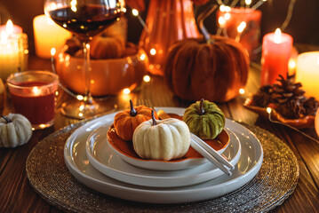 Autumnal table setting with decorative pumpkins, candles and string lights.