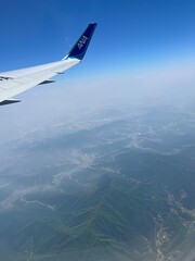 Aerial view of Seoul cityscape from ANA airplane window, urban skyline and mountains under clear blue sky, travel and adventure flight over South Korea