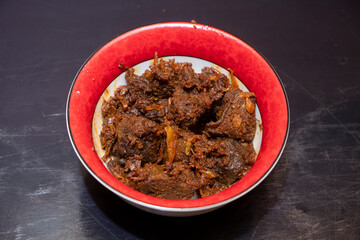 Beef Kala Bhuna A Traditional Bengali Spicy Dry Beef Curry Served in Red and White Bowl on Dark Background top view