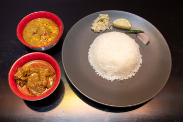 Bangladeshi plain rice with mezbani dal, beef rezala, onion salad, chili, and lemon wedge top view
