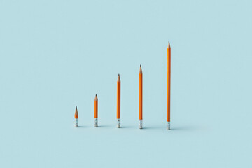 Orange pencils arranged as ascending bar graph on blue
