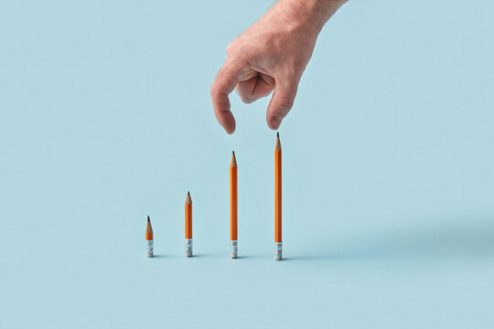 Hand reaching toward pencil bar graph on blue background