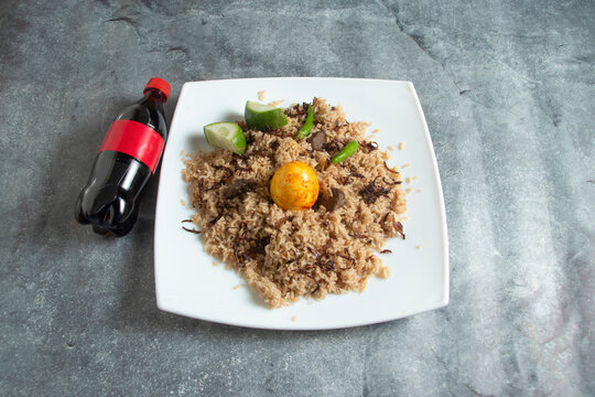 Traditional Beef Tehari Rice with Boiled Egg, Cucumber, Green Chili, and Cola Bottle cold drink top view