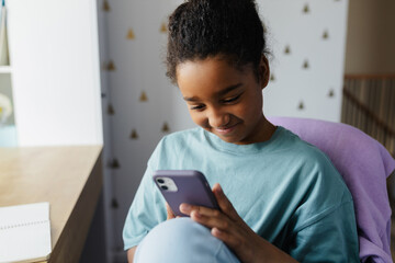 Smiling student using smartphone at home for education