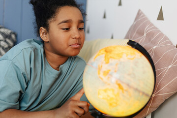 Curious young girl exploring the world with illuminated globe