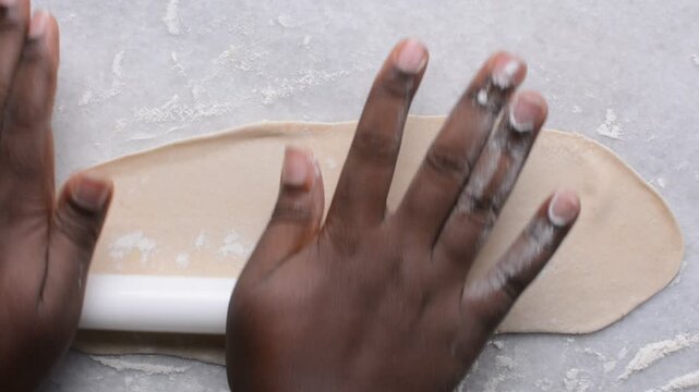 Overhead view of paratha dough being rolled out, top view of flaky flatbread dough, process of making paratha
