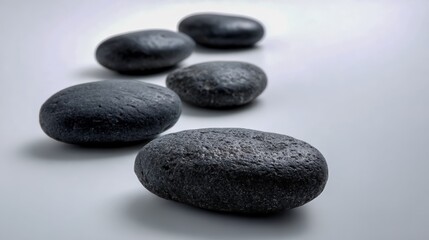 Fototapeta premium Smooth Black Stones in a Row on White Background Representing Balance and Calm for Wellness Concepts