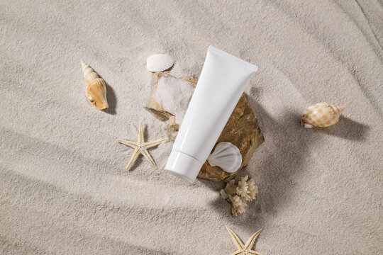 Skincare product presentation with seashells and starfish on sand