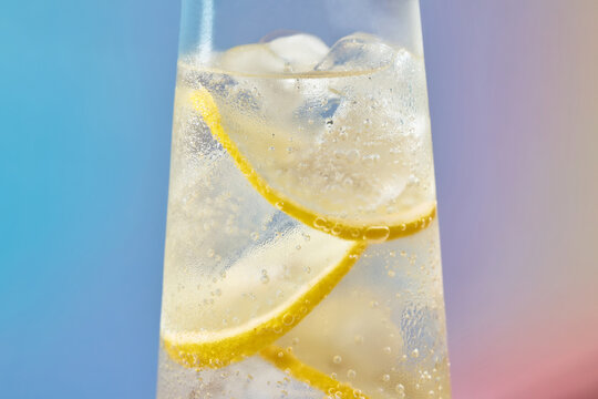 A refreshing cocktail with lemon slices and ice in a tall glass