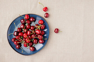 Cherries on blue plate with fabric background
