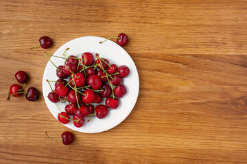 Fresh cherries on white plate top view
