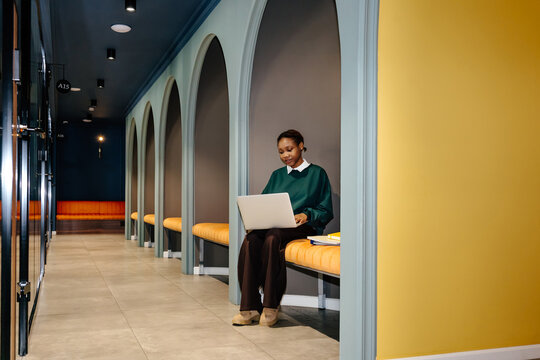 Woman With Laptop Sitting in Booth Ander Arched Walls