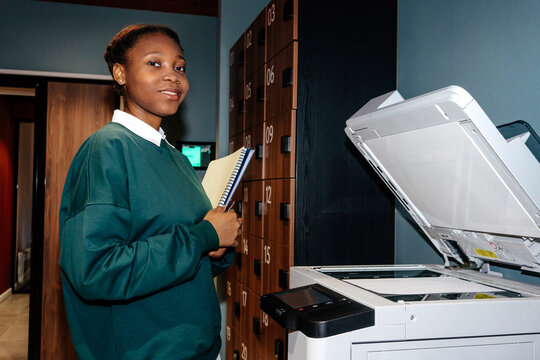 Woman standing near office copier and holding folder with documents