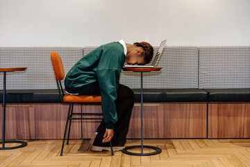 Tired woman resting head on laptop at table