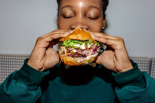 Close-up of woman taking bite out of burger