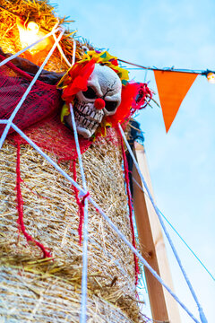 Spooky Halloween Decorations with Haybale, Skull, and Pumpkins, Isolated on Blue Sky Background