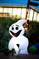 Spooky Halloween Ghost Decoration by Walkway at Night with Blurred Background of Lit-Up Building