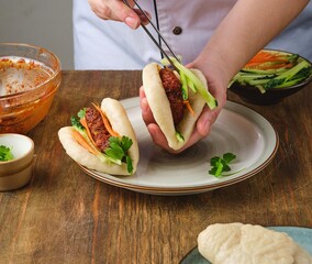 Step-by-step preparation of steamed bao buns with chicken, fresh cucumber and carrot filling on a...