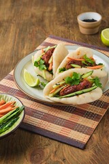 Step by step cooking of steamed bao buns stuffed with chicken, fresh cucumber and carrot on a wooden background. Ready bao buns stuffed with chicken and vegetables on a plate.
