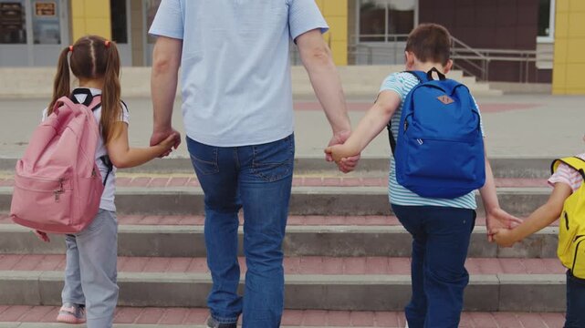 Holding hands for safety, Backpacks ready for class, Family together at crosswalk, Crossing street to school, Security in numbers, Education adventure begins, Morning family ritual, Strong sibling