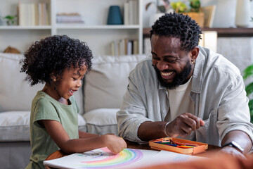 Father and daughter joyfully draw a rainbow together.