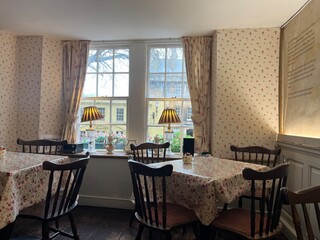 Charming vintage tearoom interior with floral tablecloths, wooden chairs, and cozy window seating overlooking a quaint street view