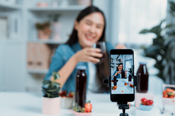 Selective focus smartphone with smiling young beautiful Asian reviewing mixed strawberry and cherry...