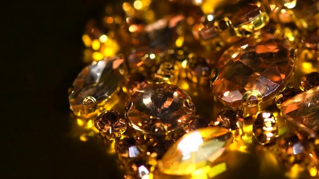 Gold crystals background, gemstones, Sew-on Stones, rhinestones for clothes, blinking gems on black background, rotating backdrop. Closeup 
