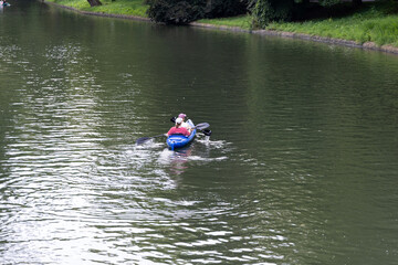 Two individuals are kayaking on a serene river, surrounded by lush greenery and reflecting water,...
