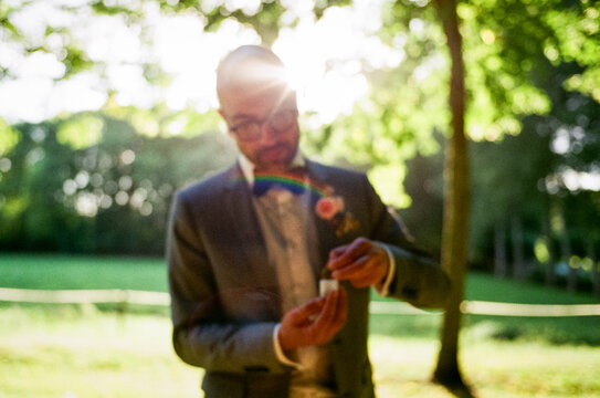 Groomsman in Suit Prepares for Ceremony rolling a joint