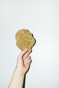 Hand holding natural authentic bath washing shower sponge with flash