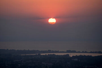 hazy misty sunset in orange and red over Lake Constance seen from high up in Bildstein, Vorarlberg ,Austria