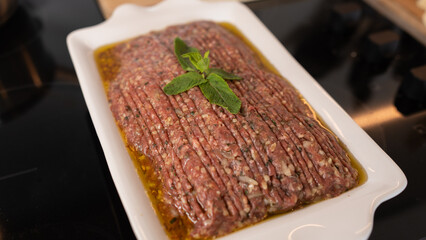 Succulent beef kibbeh nayeh, a Middle Eastern delicacy of finely minced raw beef with bulgur, spices, and olive oil, served with fresh herbs and pita. Traditional Lebanese raw meat dish.