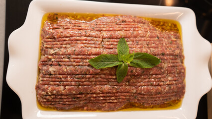 Succulent beef kibbeh nayeh, a Middle Eastern delicacy of finely minced raw beef with bulgur, spices, and olive oil, served with fresh herbs and pita. Traditional Lebanese raw meat dish.