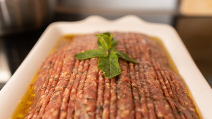 Succulent beef kibbeh nayeh, a Middle Eastern delicacy of finely minced raw beef with bulgur, spices, and olive oil, served with fresh herbs and pita. Traditional Lebanese raw meat dish.