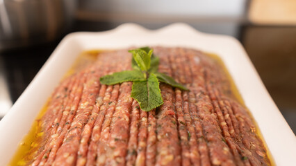 Succulent beef kibbeh nayeh, a Middle Eastern delicacy of finely minced raw beef with bulgur, spices, and olive oil, served with fresh herbs and pita. Traditional Lebanese raw meat dish.
