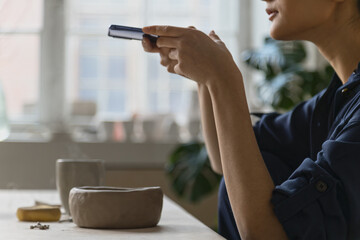 Portrait of ceramic artist using mobile phone in studio