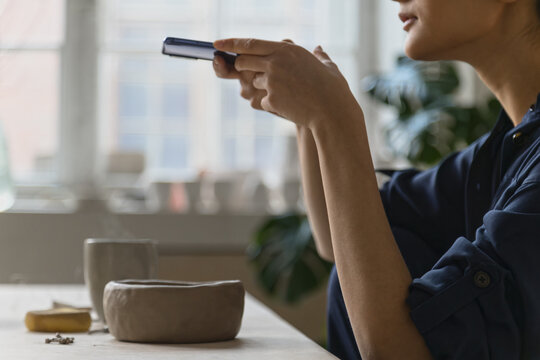 Portrait of ceramic artist using mobile phone in studio