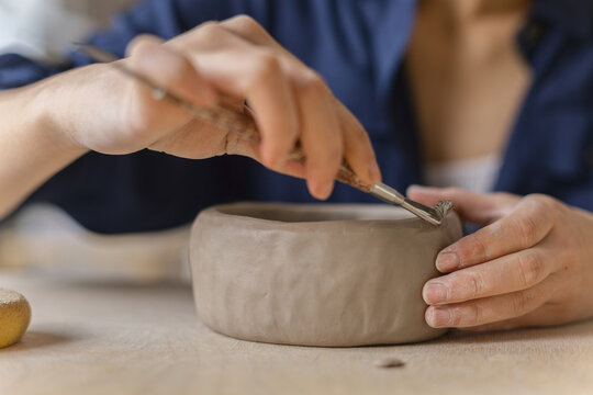 Female ceramics artisan uses loop tool for sculpting clayware