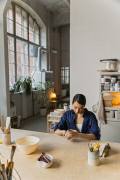Female Asian ceramics artisan kneads a piece of clay