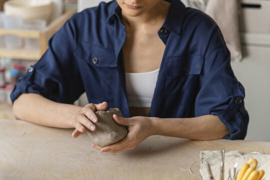 Female Asian ceramics artisan kneads a piece of clay