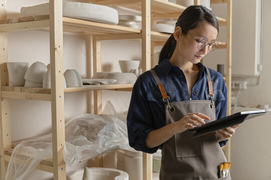 Portrait of ceramic artist using computer tablet in studio